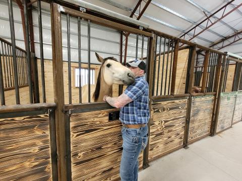 A man pets a therapy horse in a stable
