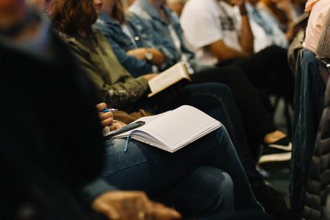 People sitting in a presentation with notebooks