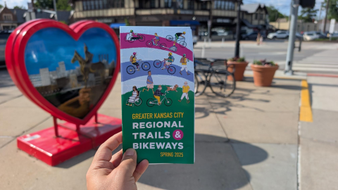 2025 bike map in print in front of Kansas City heart sculpture